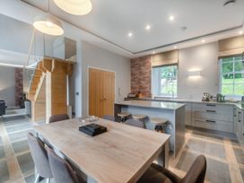 A kitchen with dining table and bar stools at Coach House in Praze-An-Beeble