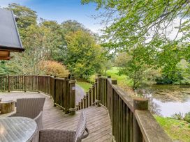An outdoor area with a wooden deck overlooking trees and a pond at The Treehouse in Praze-An-Beeble