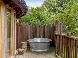 An outdoor area with a bathtub and wooden railing at The Treehouse in Praze-An-Beeble