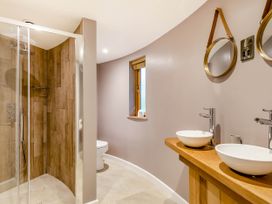 A bathroom with a shower, toilet, and sinks at The Treehouse in Praze-An-Beeble