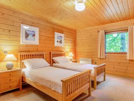 A bedroom with two single beds and a nightstand at Woodland Lodge Spa Praze-An-Beeble
