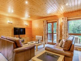 A living room with a tv and sofa at Woodland Lodge Spa in Praze-An-Beeble