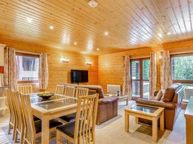 A living room with a dining table and sofa at Woodland Lodge Spa in Praze-An-Beeble