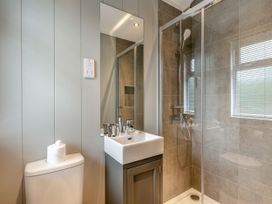 A bathroom with a toilet, sink, mirror and shower at Argel Spa Pet in Praze-An-Beeble