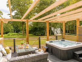 A patio with a hot tub and outdoor furniture at Kilden Pet in Praze-An-Beeble