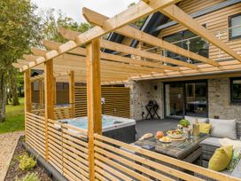 A patio area with a hot tub and dining furniture at Kilden Pet in Praze-An-Beeble