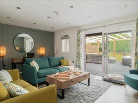 A living room with sofas and doors leading to a patio at Kilden Pet in Praze-An-Beeble