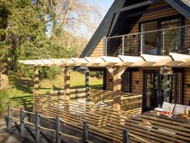 An outdoor deck with a pergola and railing at Lowarth Lodge Spa Pet in Praze-An-Beeble