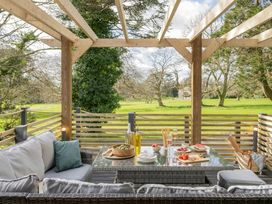 An outdoor patio with seating and dining items at Lowarth Lodge Spa Pet in Praze-An-Beeble