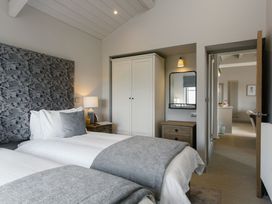 A bedroom with two beds, a lamp, and a wardrobe at Dylan Spa Laugharne