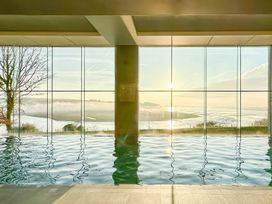 An indoor pool with large windows overlooking a landscape at Dylan Spa in Laugharne