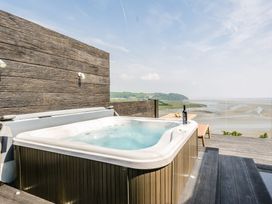 A hot tub on a wooden deck with a view of the landscape at The View in Laugharne