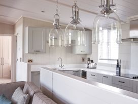 A kitchen with gray cabinets and pendant lights at Milk Wood 3 Spa in Laugharne