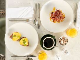 A dining table with plates of food, coffee, and juice at Milk Wood 3 Spa Laugharne