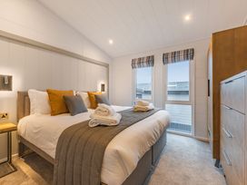 A bedroom with a bed and windows at Apex Spa Laugharne