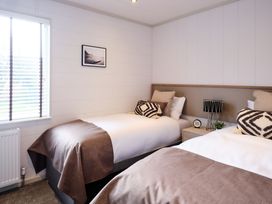 A bedroom with two beds and a lamp on a nightstand at Epic Spa (Pet) in Laugharne