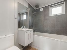 A bathroom with a sink, toilet, bathtub, and shower at Sonnet 3 Spa (Pet) Laugharne