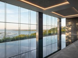 An indoor pool area with large windows overlooking water at Canto Spa in Laugharne