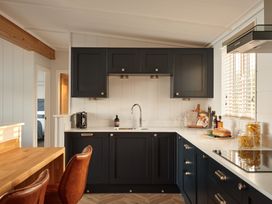 A kitchen with cabinets, sink, and cooking items at Canto Spa (pet) Laugharne