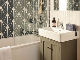 A bathroom with a bathtub, sink, and toiletries at Canto Spa (pet) Laugharne