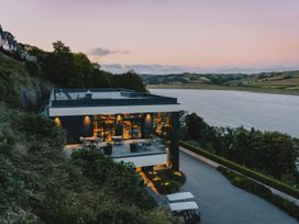 A building with a patio overlooking water at Canto Spa (pet) Laugharne
