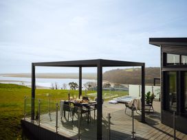 A pergola with a dining set on a deck near a hot tub at Apex Spa (Pet) Laugharne
