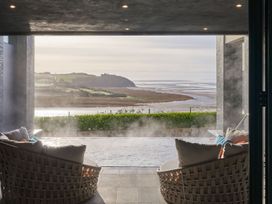An outdoor area with chairs overlooking a water view at Apex Spa (Pet) Laugharne