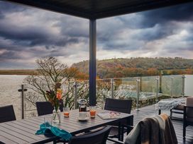 An outdoor seating area with a table and chairs overlooking a river at Wilde in Laugharne