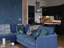 A living room with a blue sofa and kitchen area at Wilde in Laugharne
