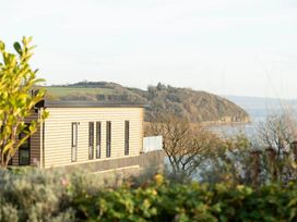 A building with a glass railing overlooking trees and hills at Solace in Laugharne