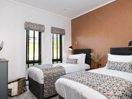 A bedroom with two beds and a flower vase at Solace in Laugharne