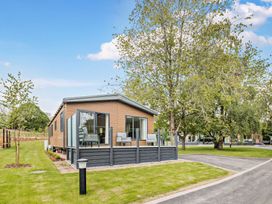 A mobile home with a deck and trees in an outdoor area at Saron 2.0 Pet in Llandyrnog