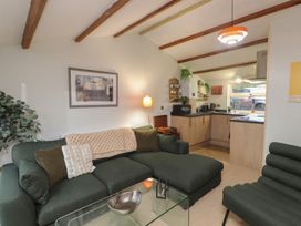 A living room with a sofa and kitchen area at 20 Chatham Log Cabins in Caernarfon
