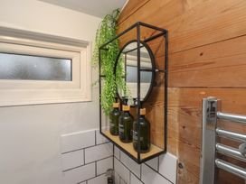A bathroom with a mirror, shelf, bottles, and a window at 20 Chatham Log Cabins, Caernarfon