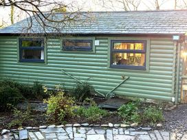 An exterior view of a green log cabin with windows at 20 Chatham Log Cabins in Caernarfon
