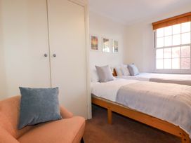 A bedroom with two beds and a chair at Chapel Cottage in Mevagissey