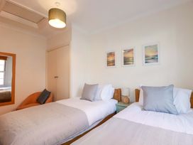 A bedroom with two beds and paintings on the wall at Chapel Cottage in Mevagissey