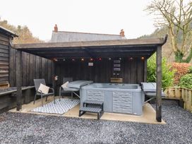 An outdoor area with a hot tub and chairs at Lodge at Nadur Commins Coch near Machynlleth