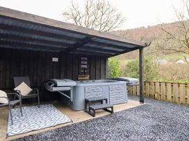 An outdoor area with a hot tub and chairs at Lodge at Nadur Commins Coch near Machynlleth