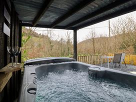 A hot tub with glasses and a table in an outdoor area at Lodge at Nadur Commins Coch near Machynlleth