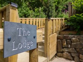 A sign for The Lodge in an outdoor area near steps and a stone wall at Lodge at Nadur Commins Coch near Machynlleth