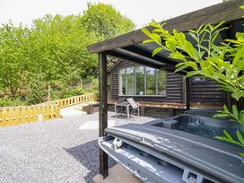 An outdoor area with a hot tub and seating at Lodge at Nadur Commins Coch near Machynlleth