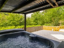 An outdoor area with a hot tub and gravel patio at Lodge at Nadur, Commins Coch near Machynlleth