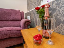 A living room with a sofa, flowers, and champagne at Sunnyvale House in Whitby