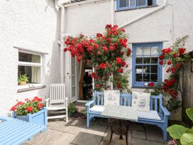 An outdoor patio with a blue chair and flowering plants at Bryn Tegid in Beaumaris