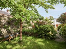 A garden with a tree and benches at Bryn Tegid Beaumaris