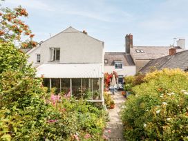 A garden with a greenhouse and flower beds at Bryn Tegid in Beaumaris