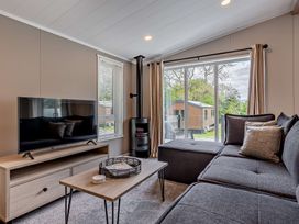 A living room with a sofa and television at Saron 2.0 Spa Pet in Llandyrnog