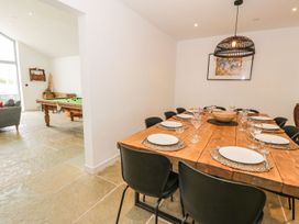 A dining room with a large table set for dinner and a pool table at Cae Sam in Pentraeth