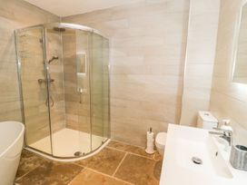 A bathroom featuring a shower, bathtub, toilet, and sink at Cae Sam in Pentraeth